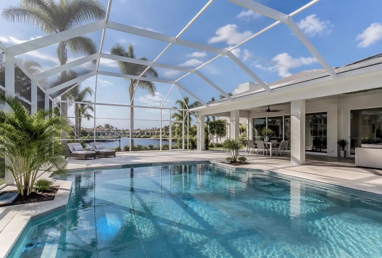 Illustrative white aluminum screen pool enclosure attached to a modern Florida home overlooking the water